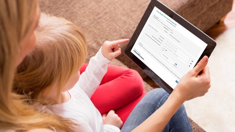 Little girl helping her mum fill out a form on the iPad