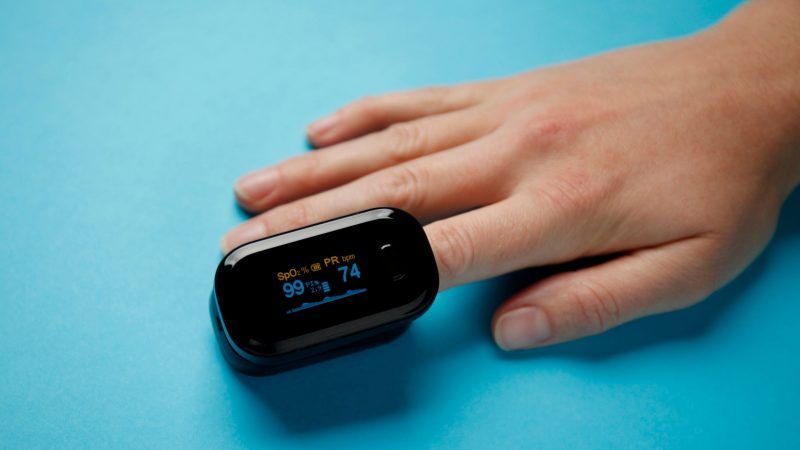 Pulse oximeter on finger with a blue background for Oximetry @ Home and COVID-19