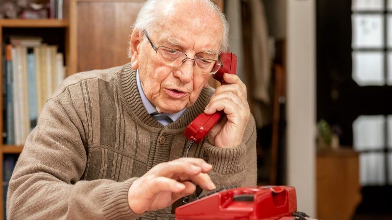 Old gentlemen using a red push button landline phone