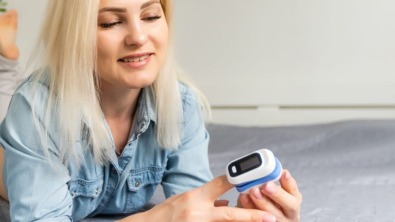 Young blonde lady with blood oximeter on finger