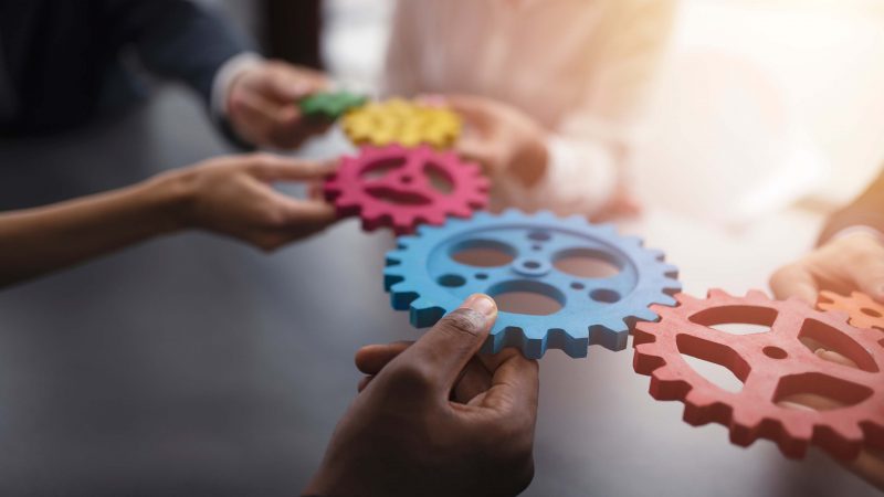 Group of people holding cogs together